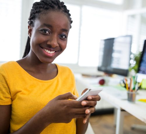 Female graphic designer using mobile phone in office